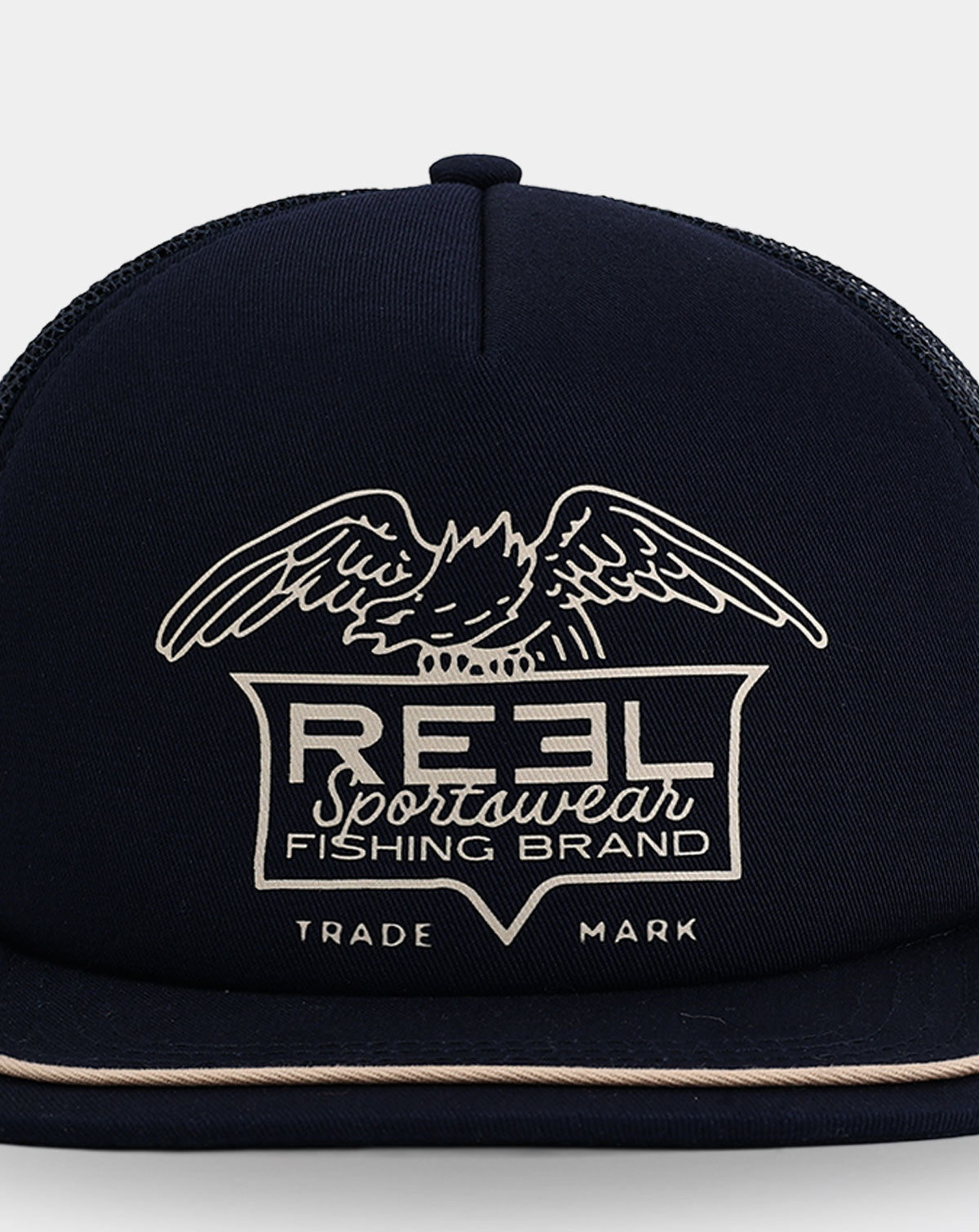 Reel Sportswear Bosun Trucker Hat — close-up of vintage eagle badge graphic with cream linework on navy structured front panel