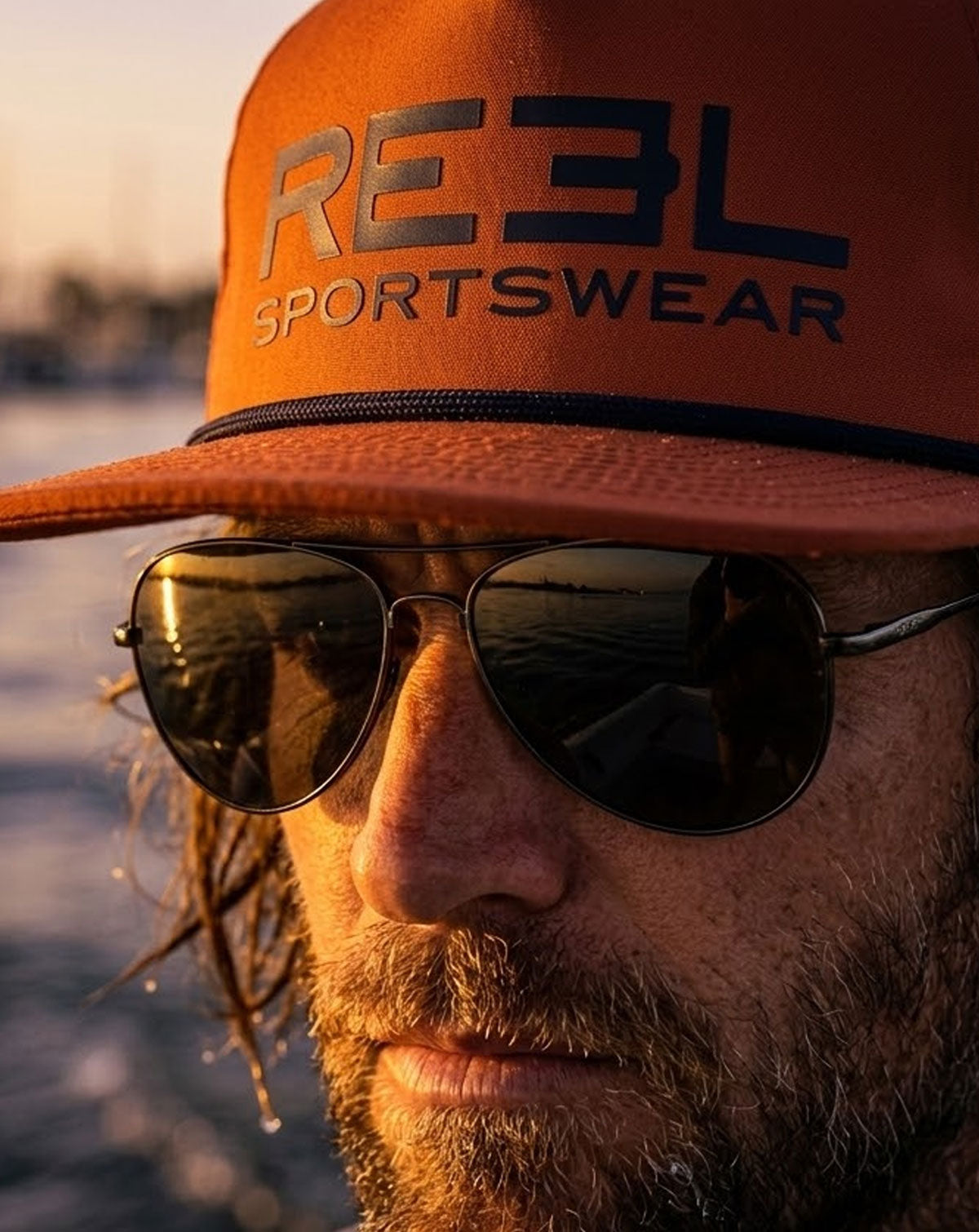 Orange cap with 'REEL Sportswear' logo on a light gray background