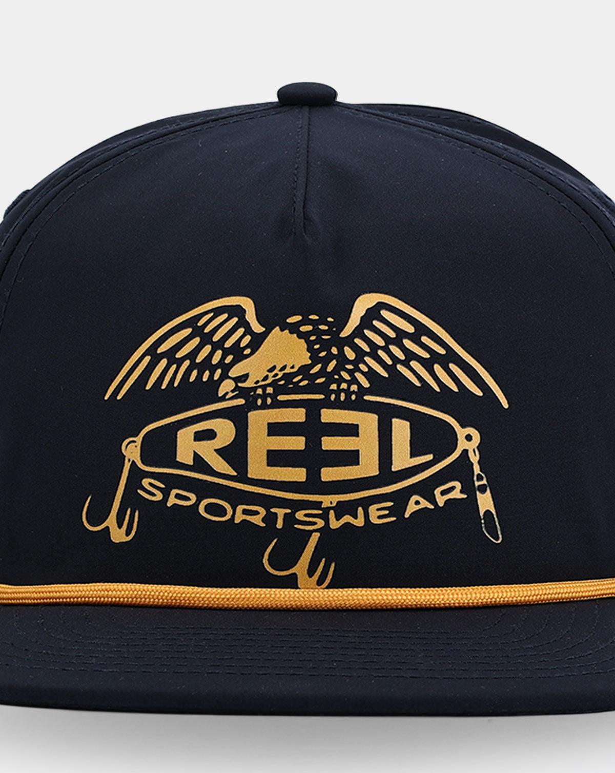 Reel Sportswear El Capitan Hat — close-up of gold eagle over oval lure badge with treble hooks and swimbait detail printed on navy nylon