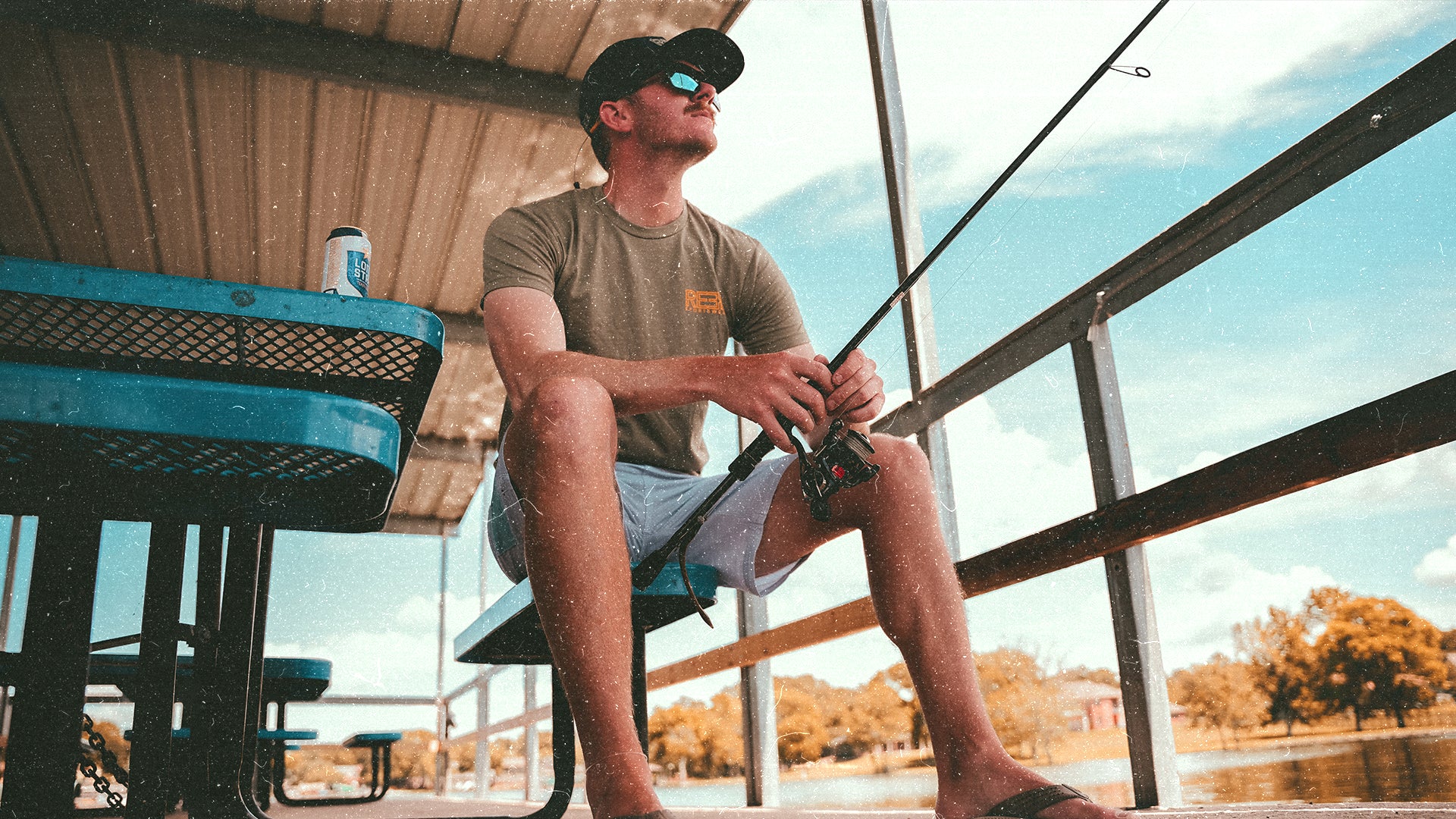 Reel Sportswear - Fisherman sitting on a dock wearing a reel sportswear fishing tee