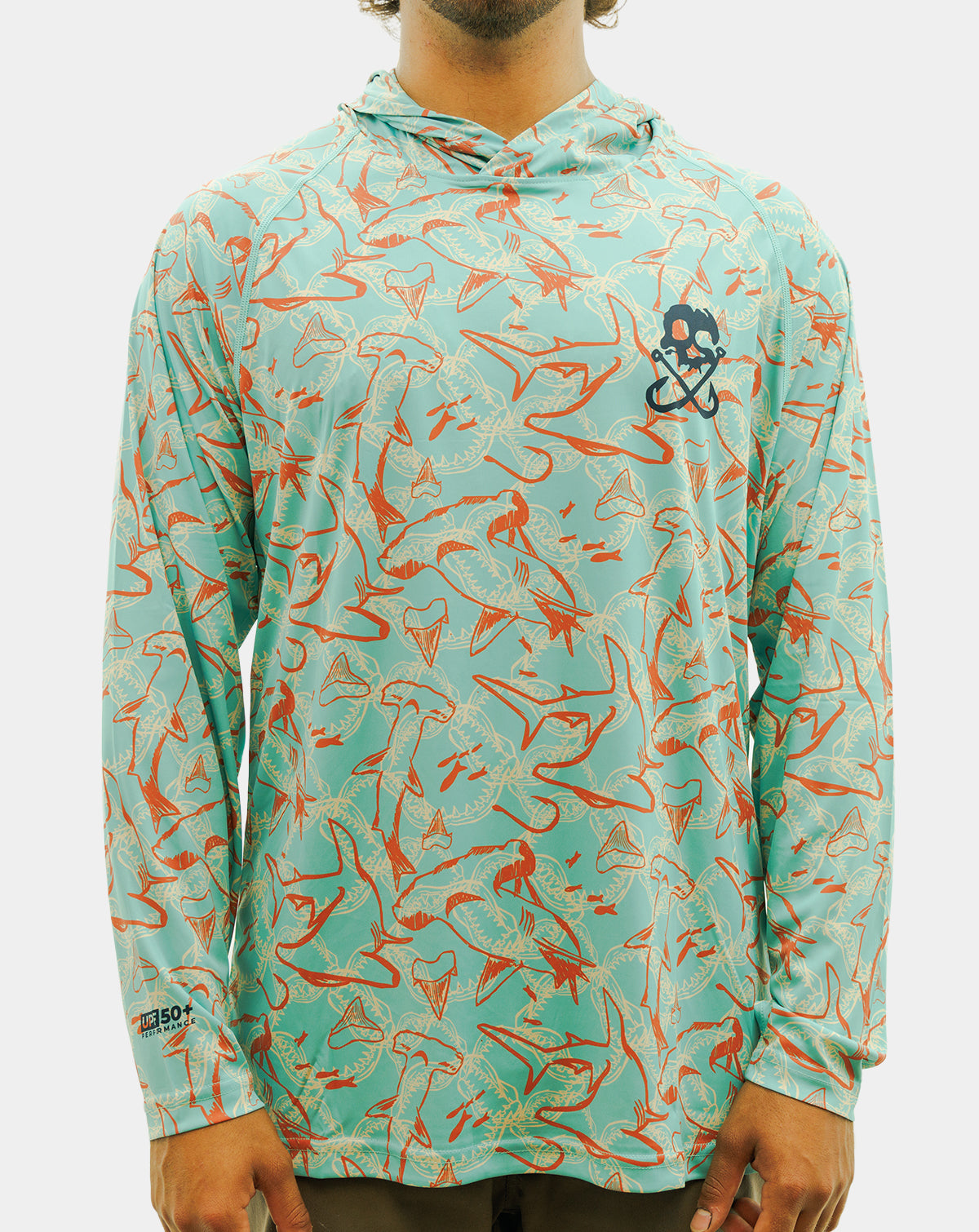 A man wearing a long-sleeve hooded performance shirt with a turquoise and orange fish pattern, featuring a black and white skull-and-crossbones logo on the left chest. Reel Sportswear Scurve fishing Hoody
